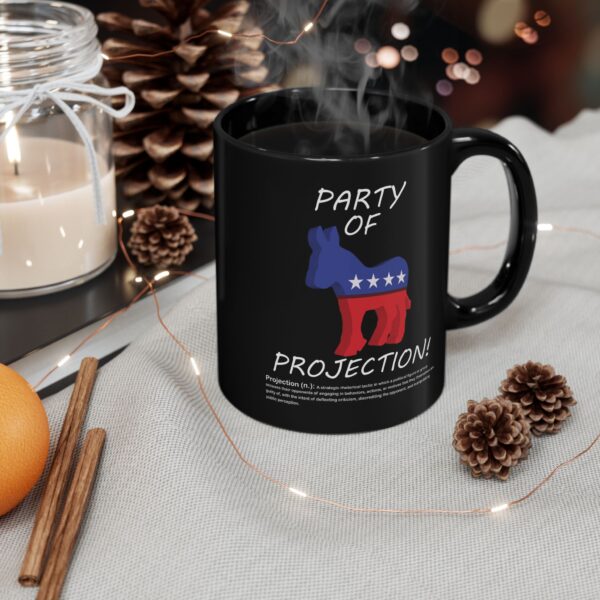 Party Of Projection black ceramic mug with white text on table next to scented candle