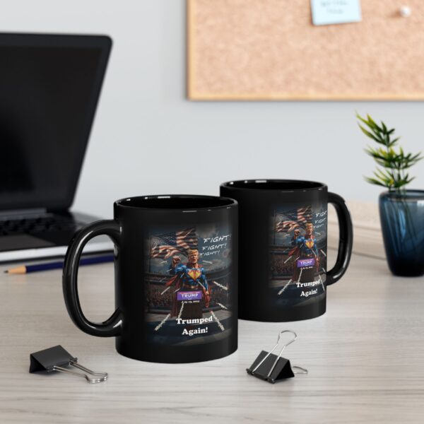 Two Trumped Again mugs black ceramic on a table next to a laptop computer