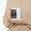 Woman in beige color sweater holding a Trumped Again! White ceramic mug with one hand